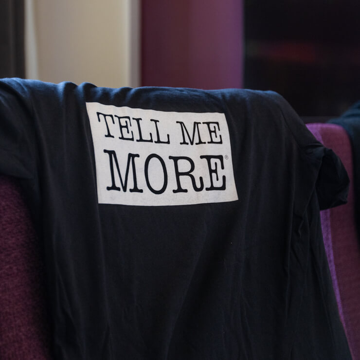 Tell me More T-shirt on a chair in a conference room