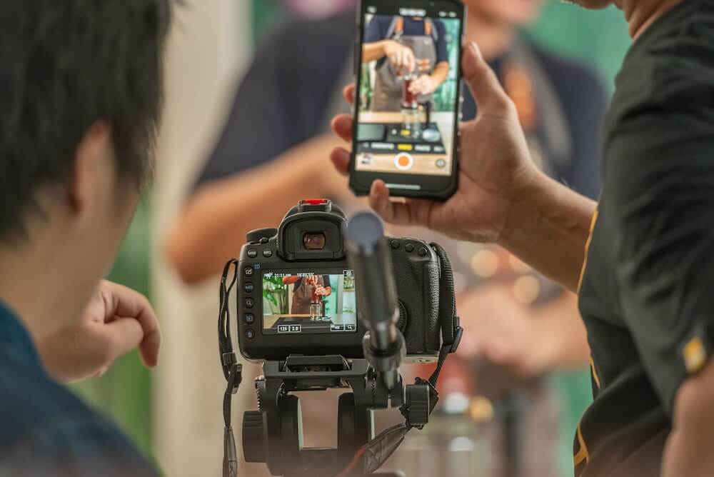 ideographer recording video clip with a camera and smartphone, highlighting the importance of capturing short clips for social media engagement.